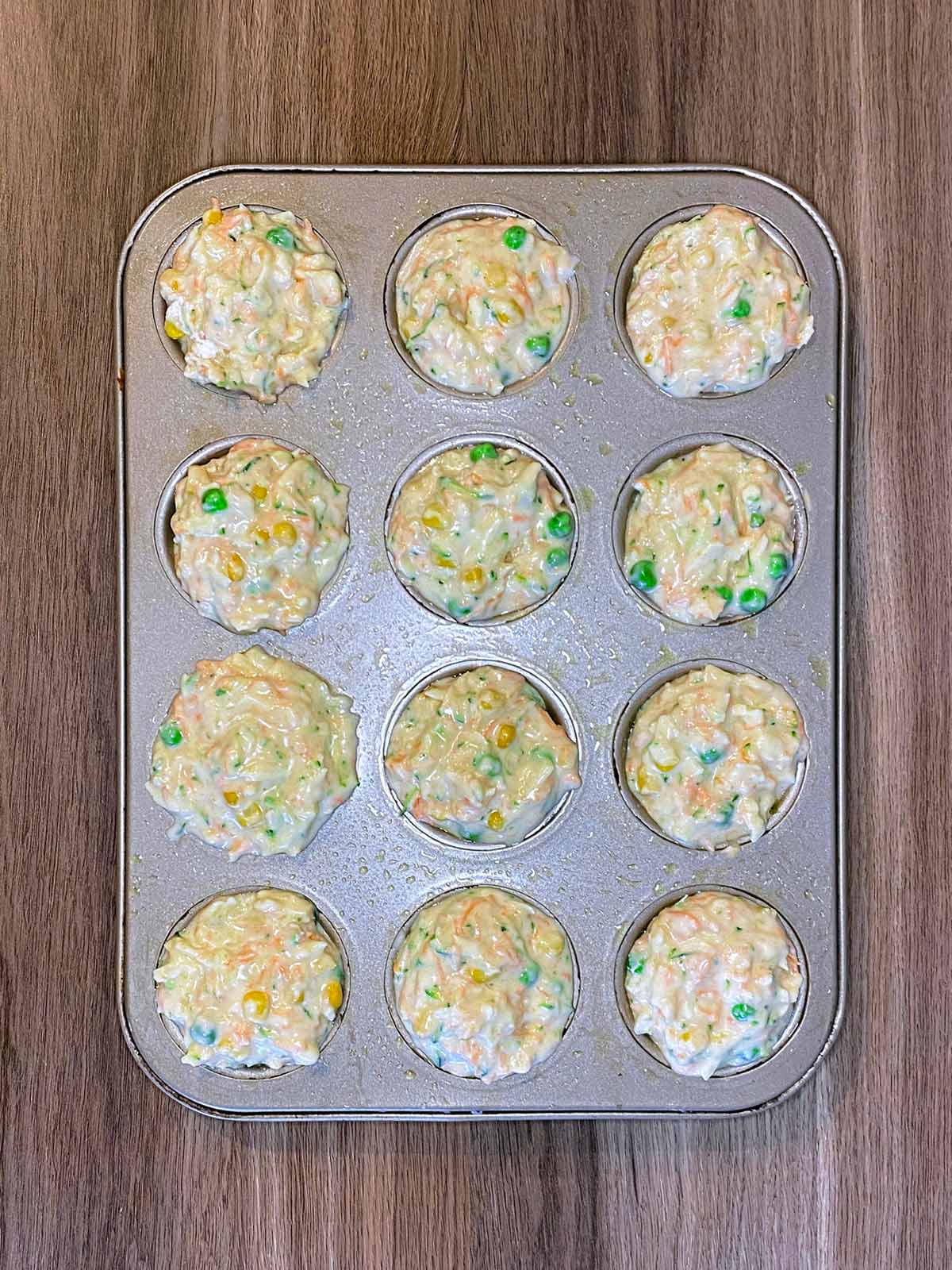 A twelve hole muffin tin filled with the muffin mixture.