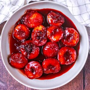 Stewed plums in a large round serving dish.