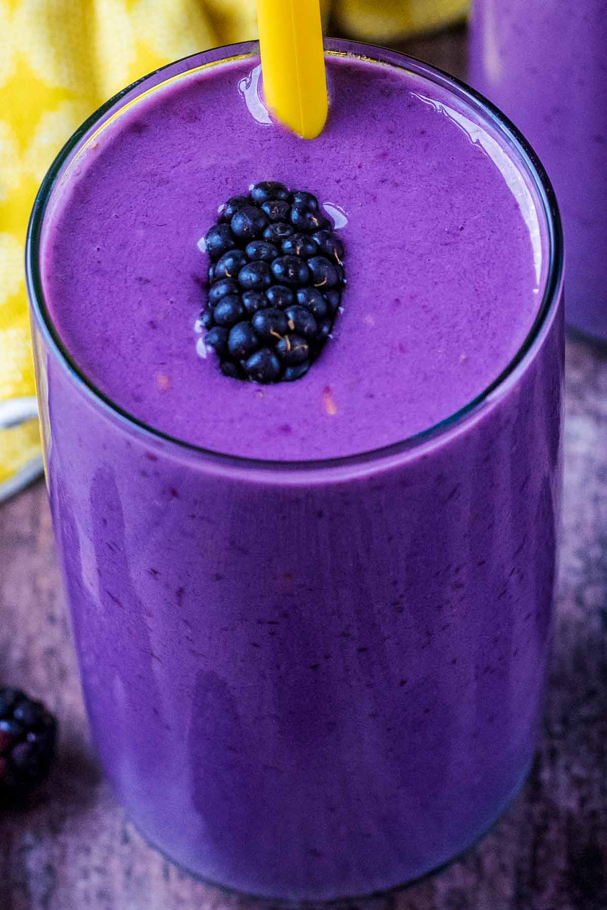 A blackberry floating on top of a purple smoothie.