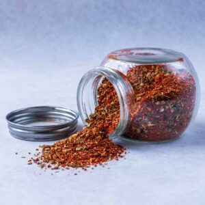 Peri peri seasoning spilling out of a glass jar.