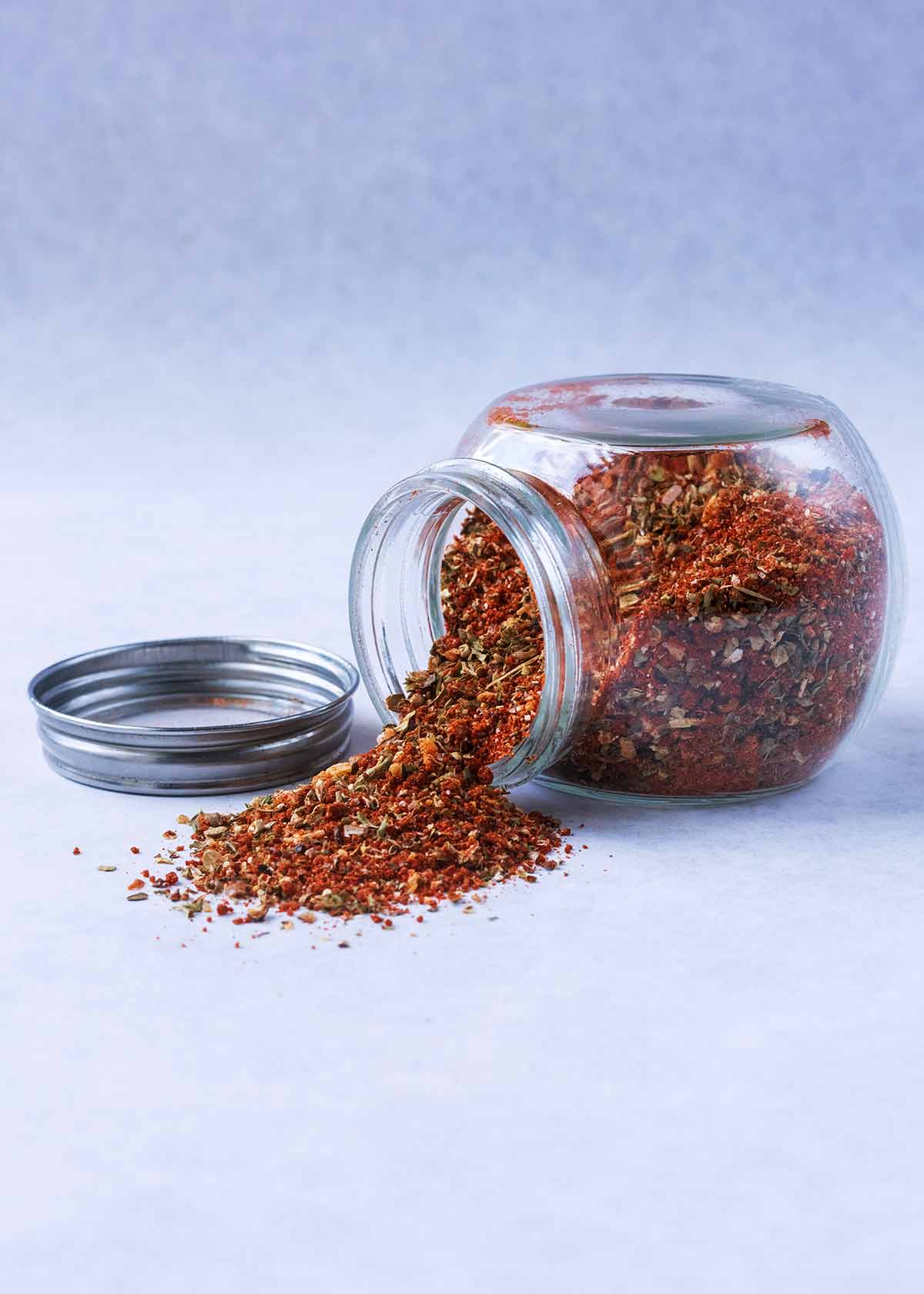 A glass jar on its side with a spice blend spilling out.
