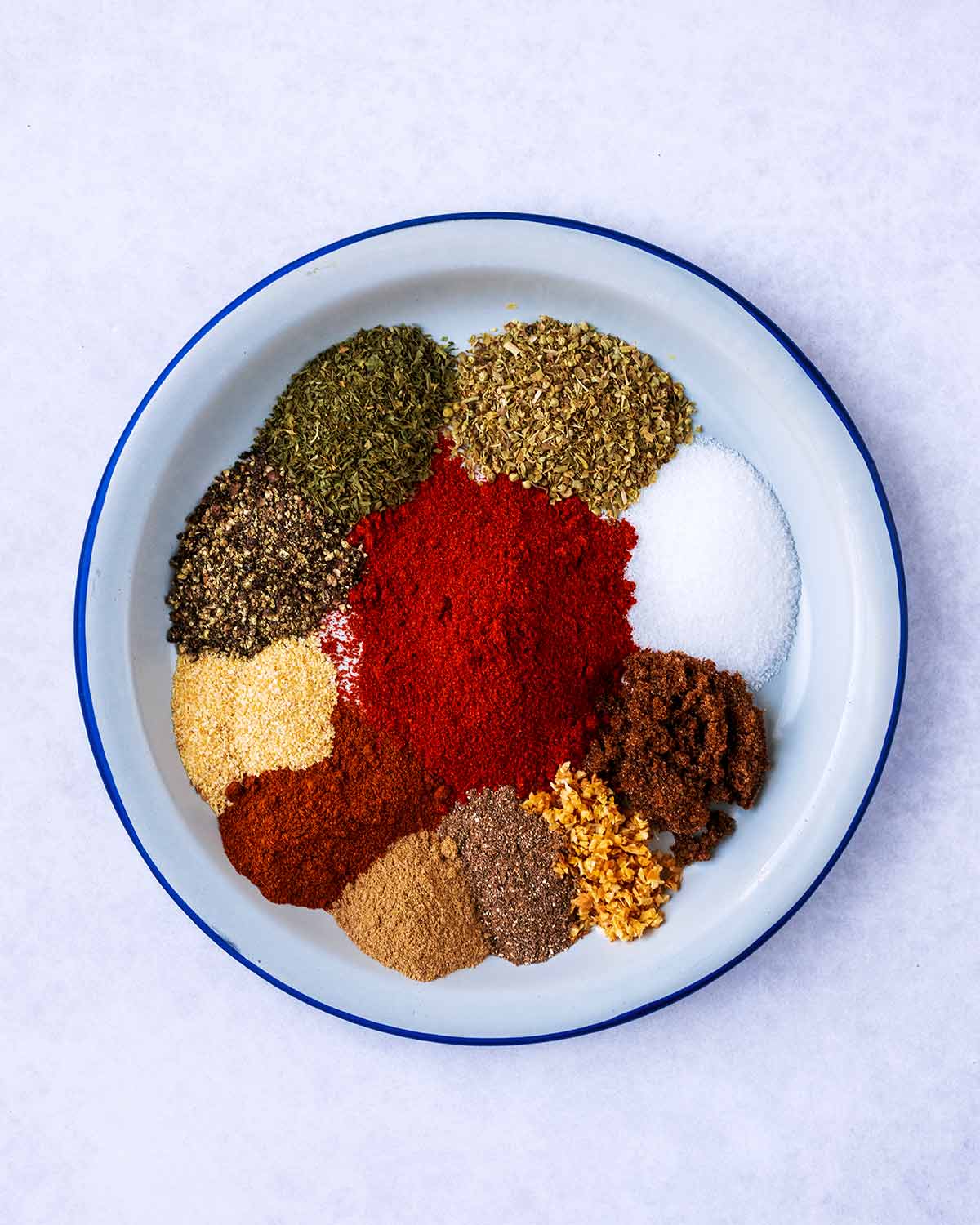 Eleven different herbs and spices on a plate.