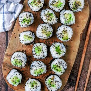 Seventeen pieces of avocado maki on a wooden serving board.