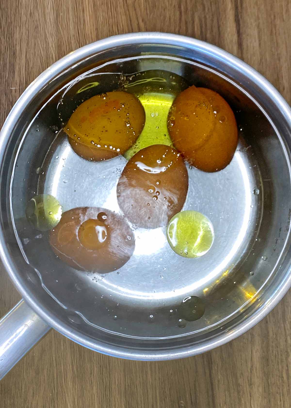 Four eggs and some oil in a pan of water.