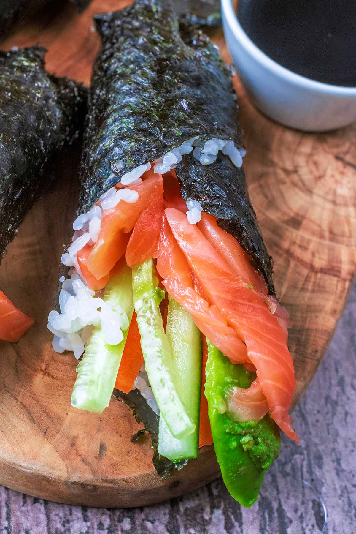Strips of salmon, cucumber, carrot and avocado poking out of a sushi roll.