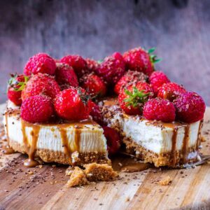 A decorated cheesecake topped with berries and caramel sauce.