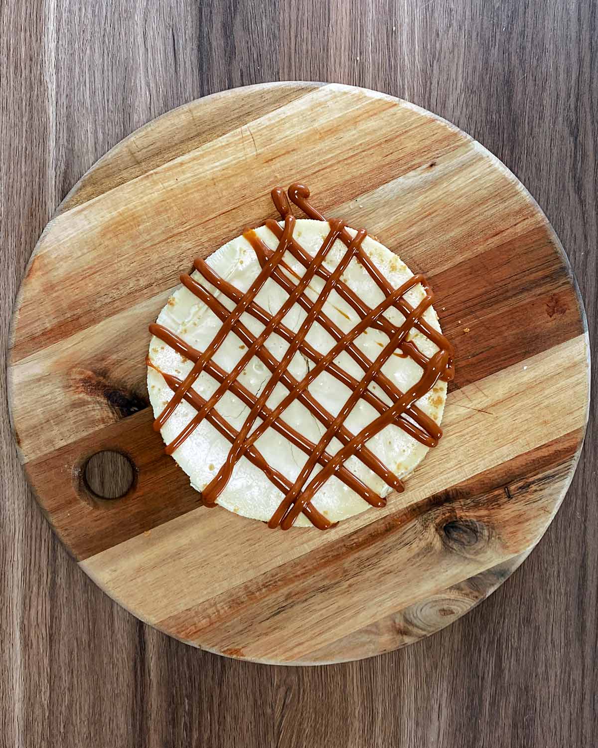 A cheesecake with a criss cross of caramel sauce over it.