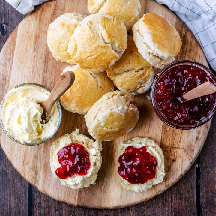 Lemonade scones on a wooden board with jam and cream.