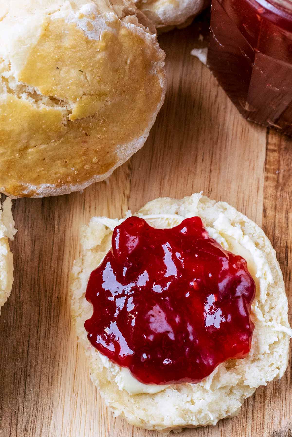 A scone topped with clotted cream and raspberry jam.