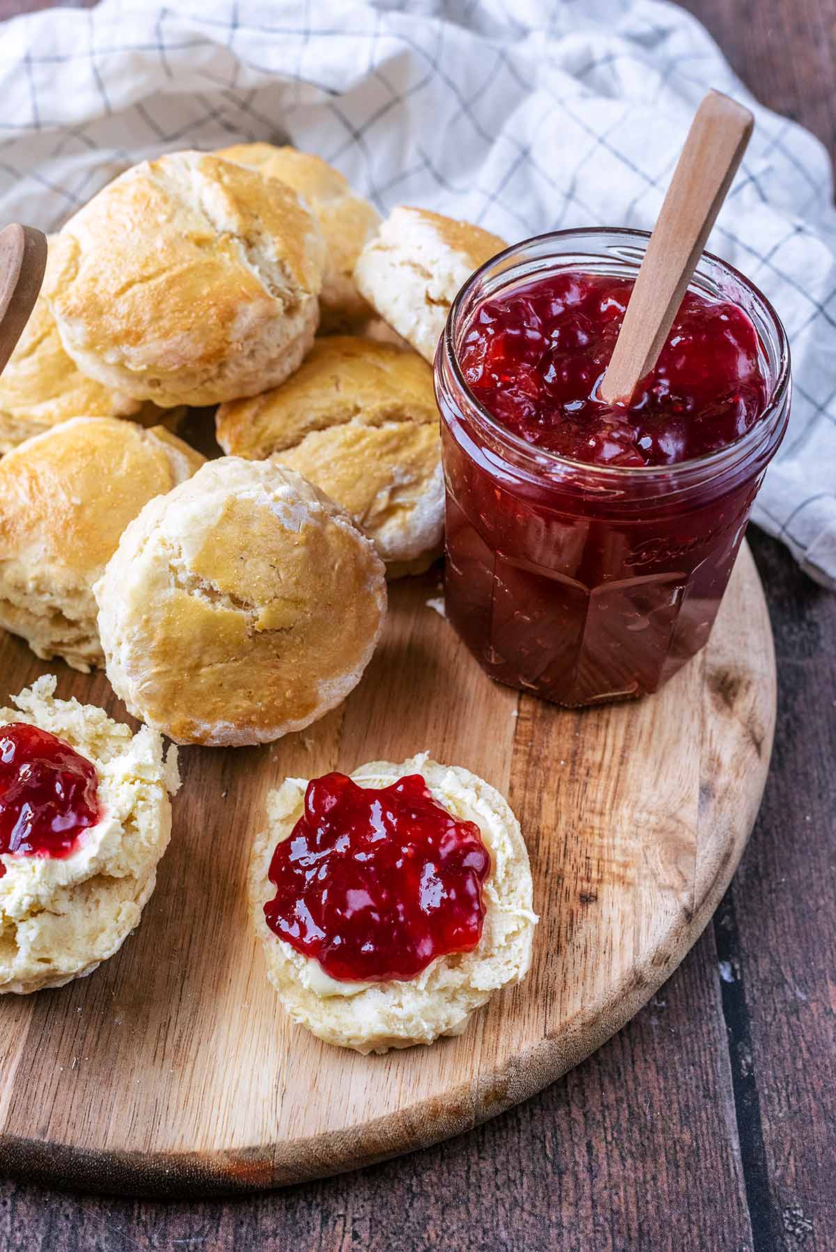Scones on a board next to a jar of jam.