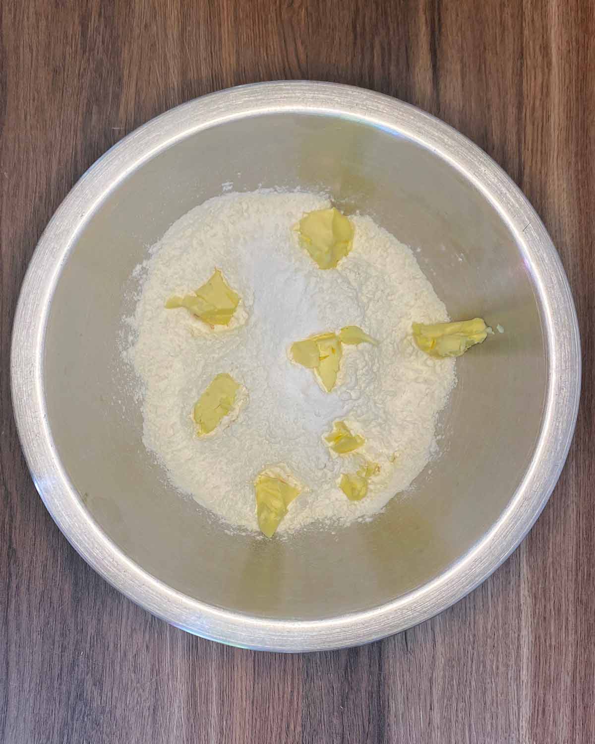 A mixing bowl with flour and butter in it.
