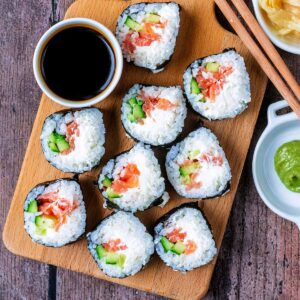 Nine pieces of Philadelphia Roll sushi on a wooden board.