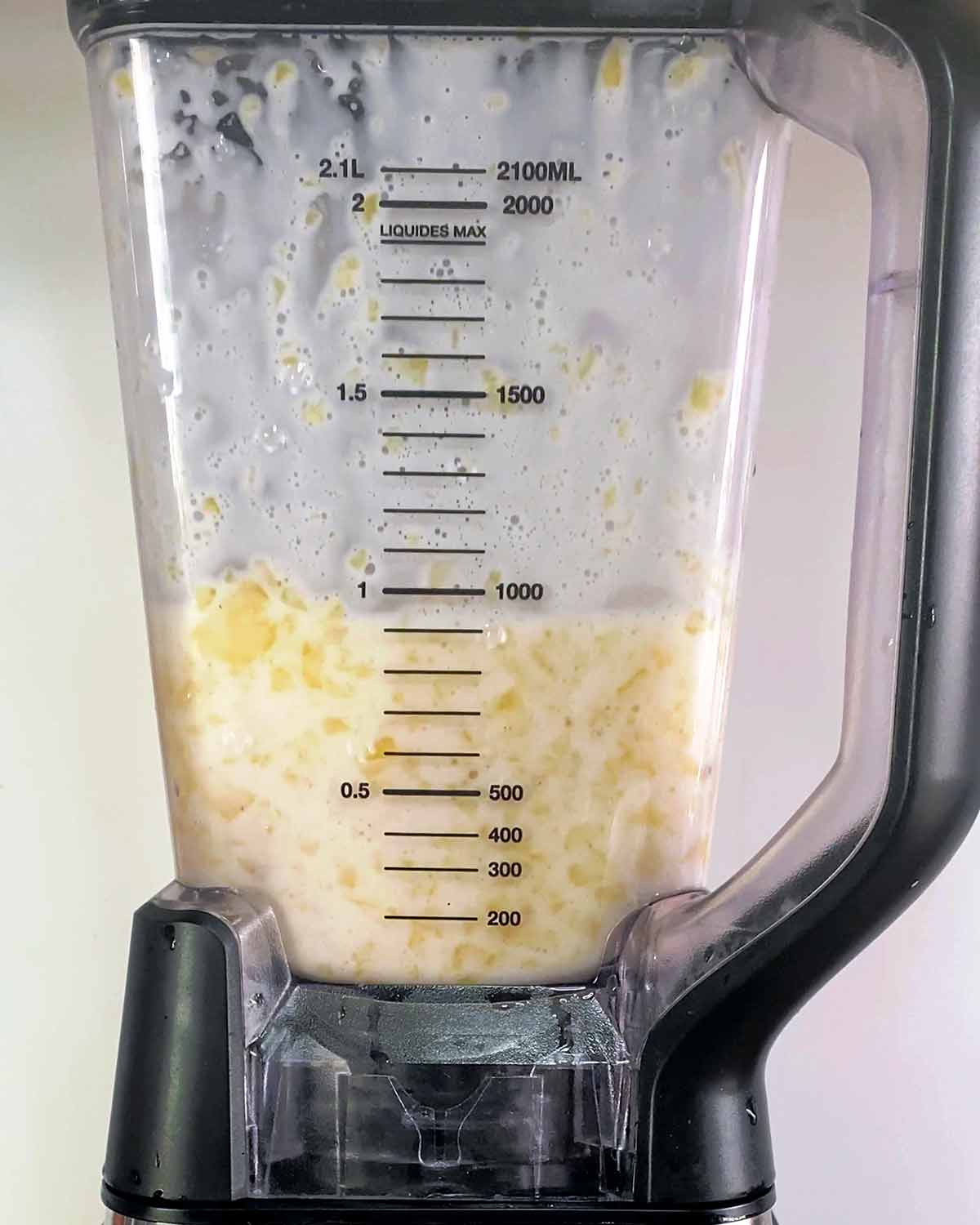 Pineapple and coconut milk blended in a blender jug.