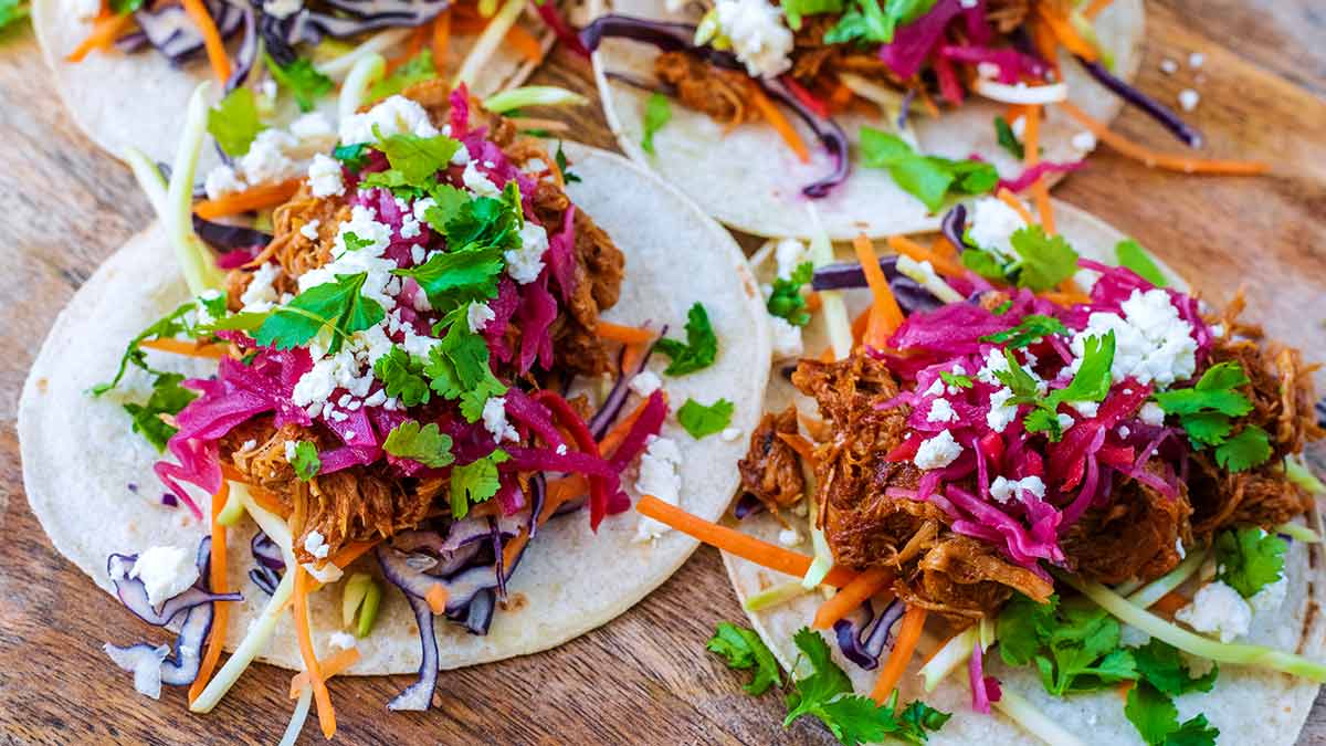 Pulled pork tacos on a wooden board.