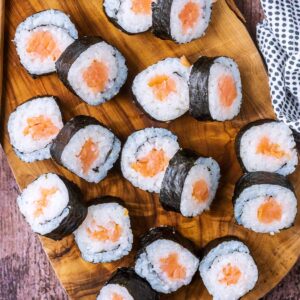 Salmon maki on a wooden serving board.