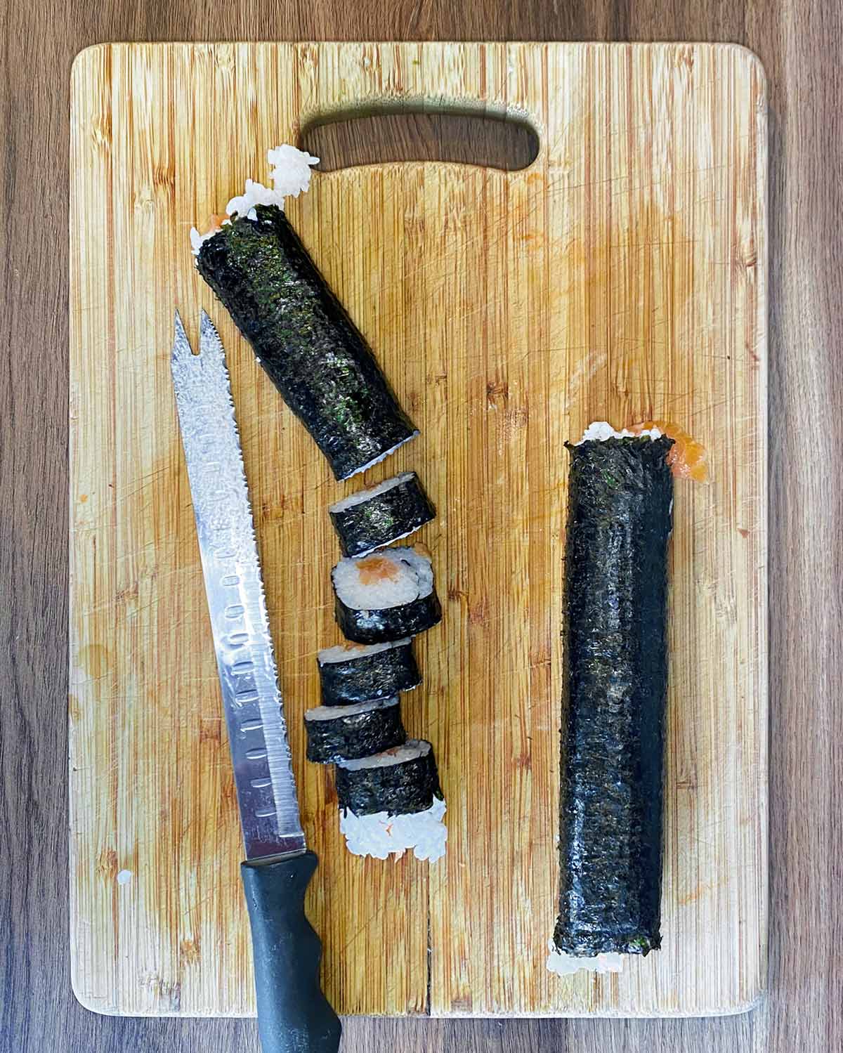 Salmon maki roll cut into pieces on a chopping board.