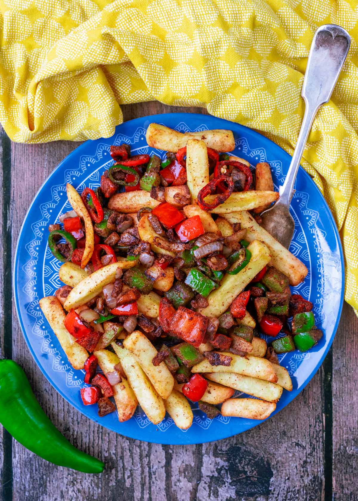 A plate of cooked chips with peppers, onions and chillies.