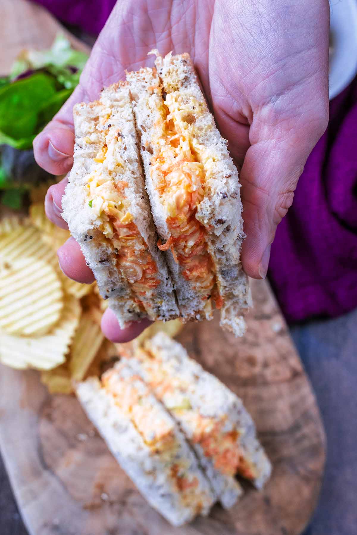 A hand holding a cheese sandwich.