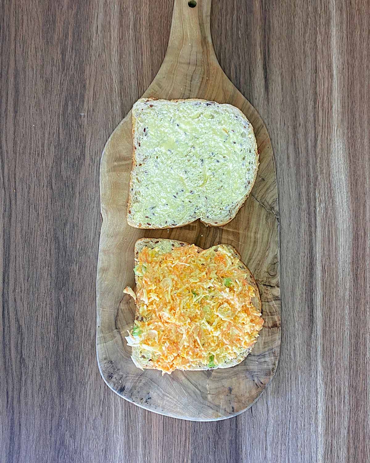 Two slices of buttered bread, one with cheese savoury mixture spread over it.