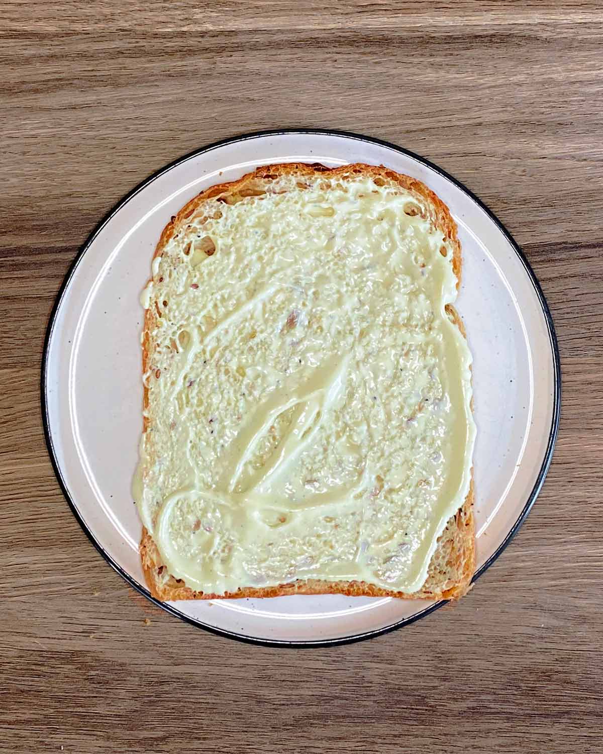 Mustard mayo spread over a slice of bread.