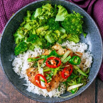 Baked fish parcel in a bowl with rice and broccoli.