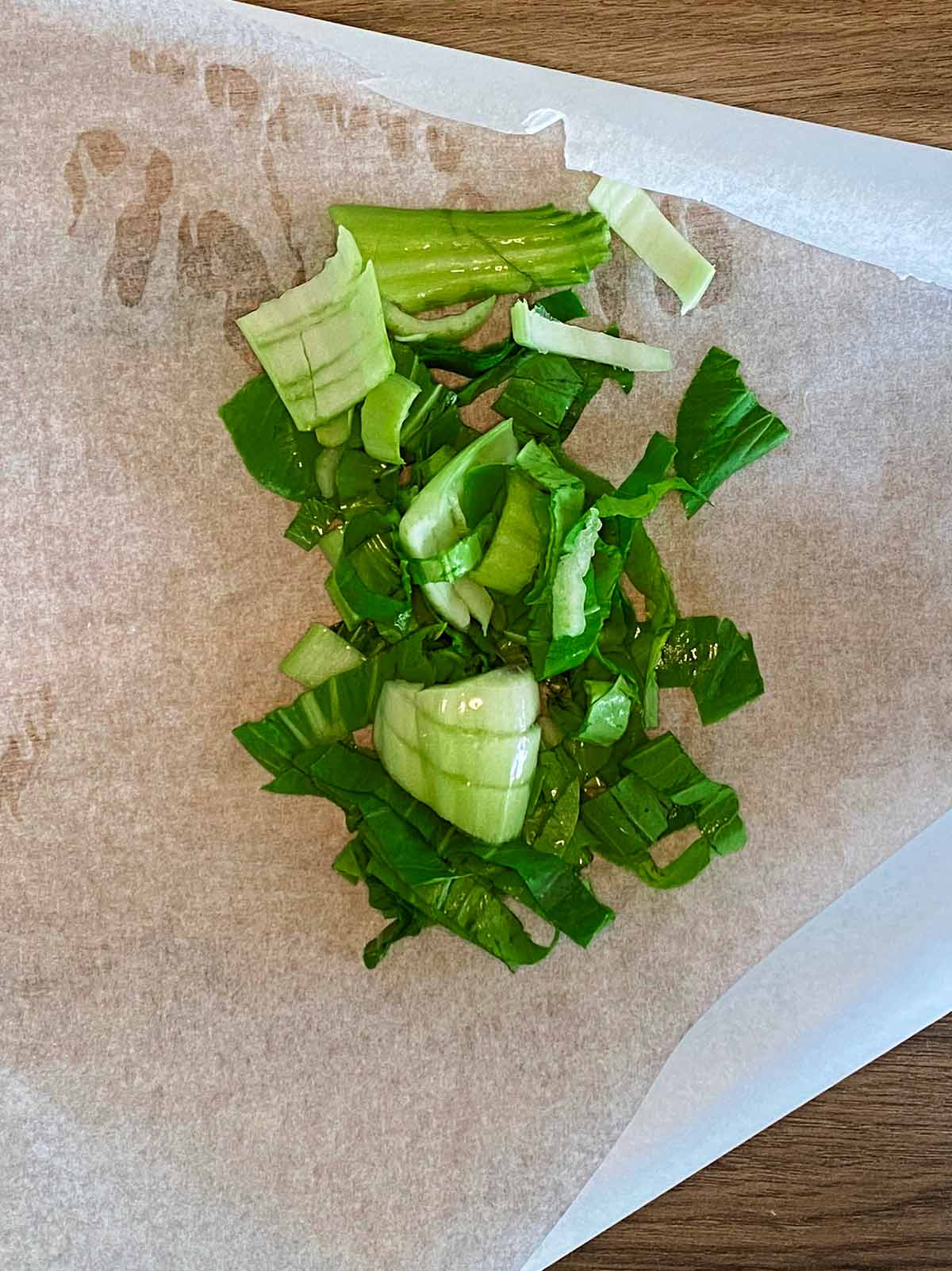 Parchment paper with chopped pak choi on it.