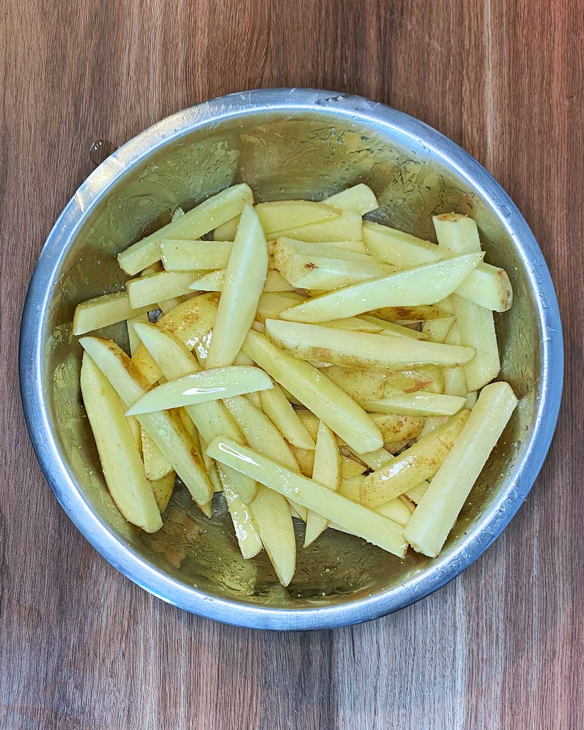 Raw chips in a bowl with oil and seasoning.