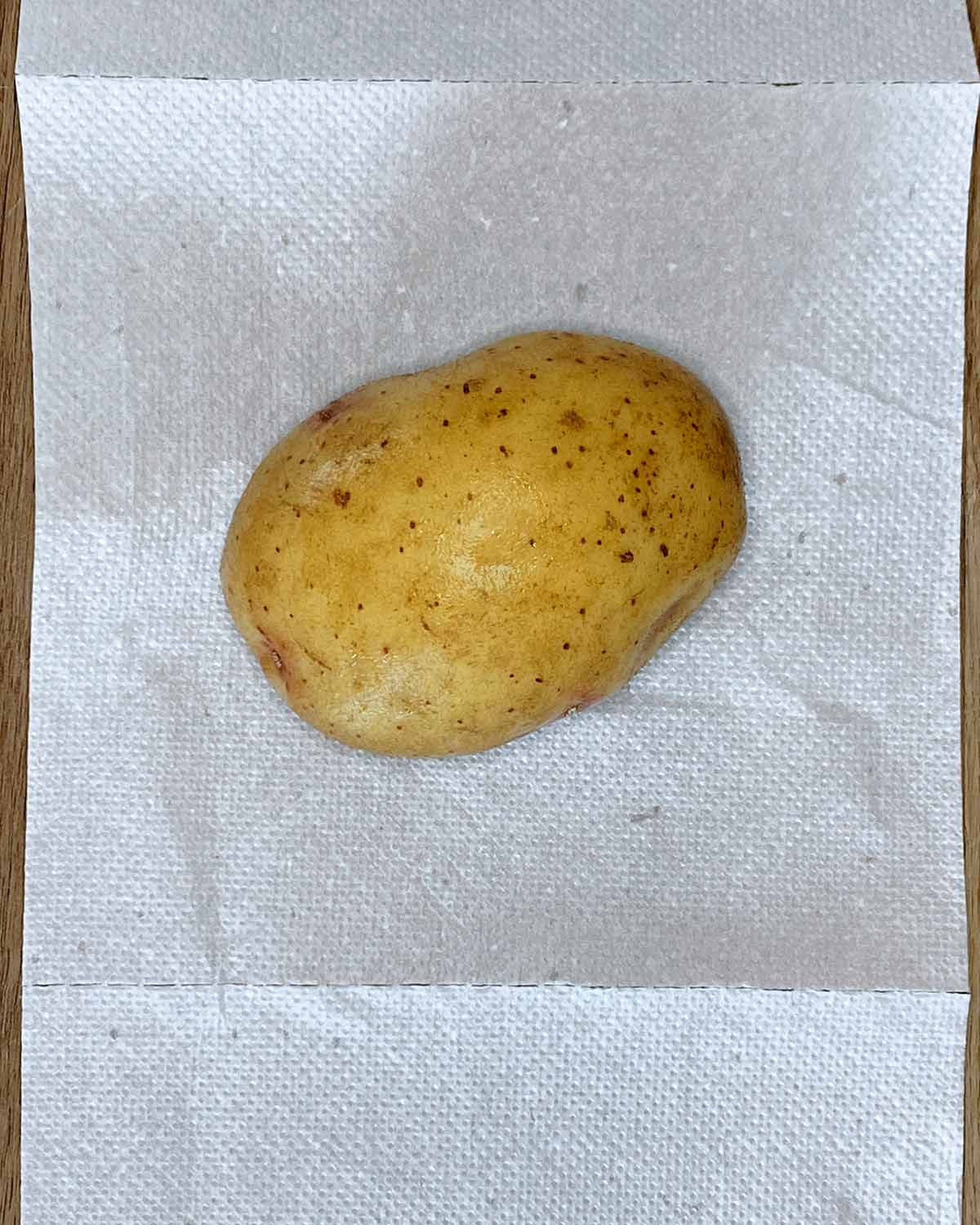 A washed potato on some kitchen towel.
