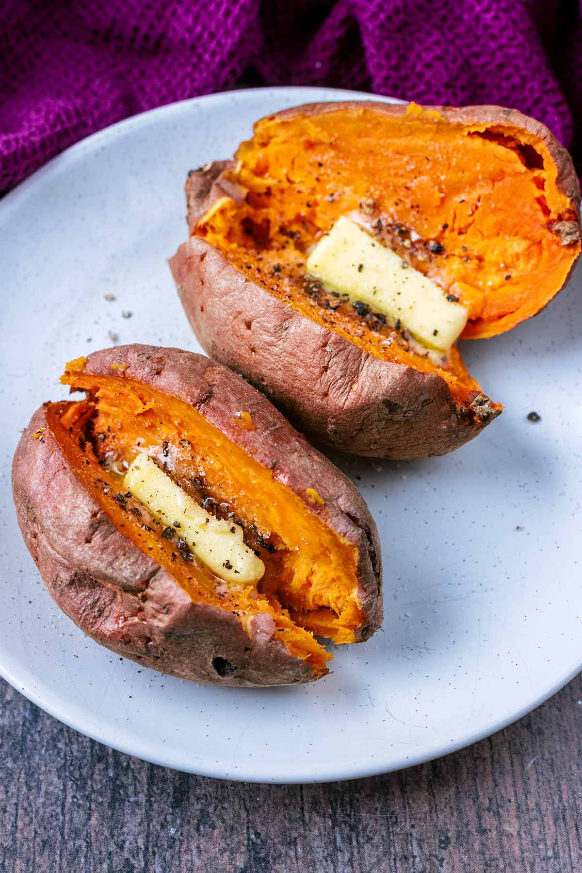 Two cooked sweet potatoes on a white plate.