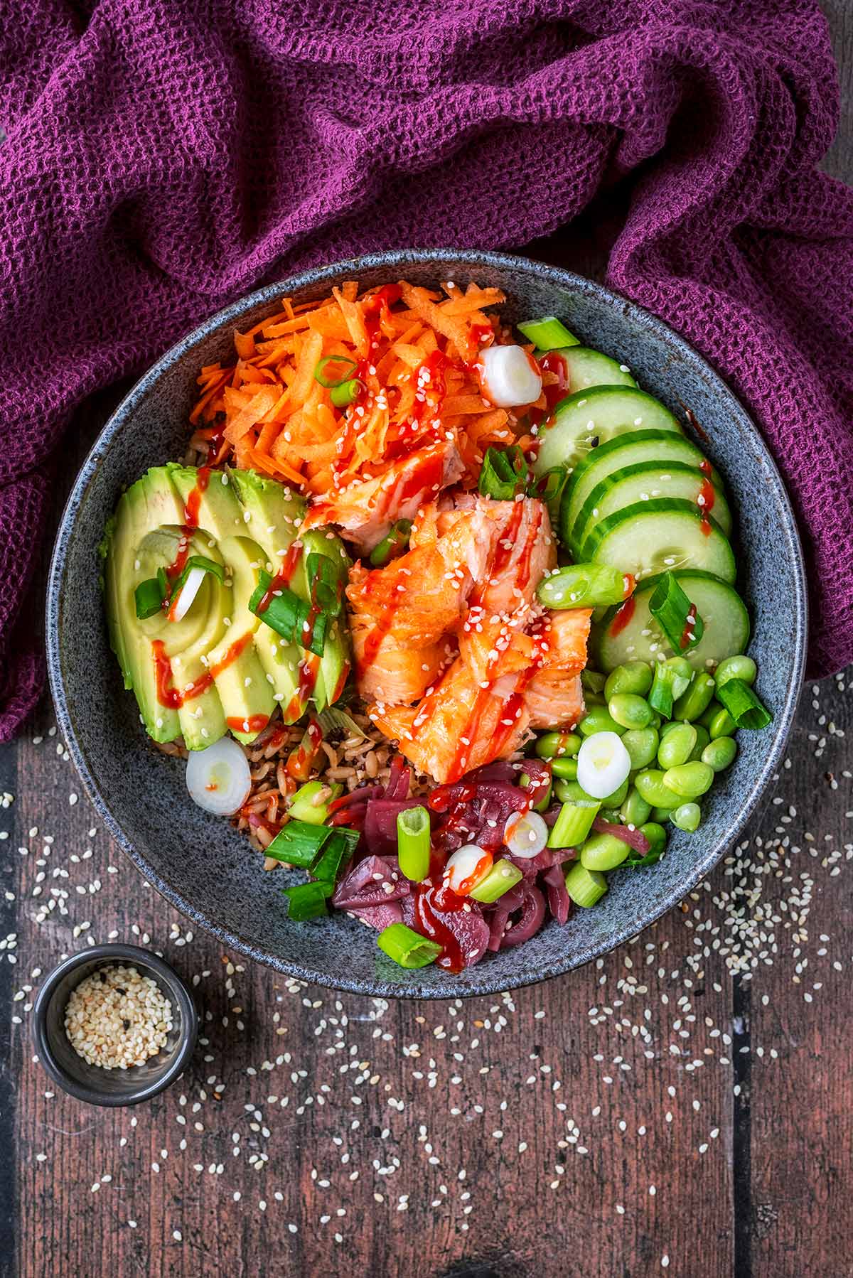 A large bowl of rice, salmon and salad vegetables.