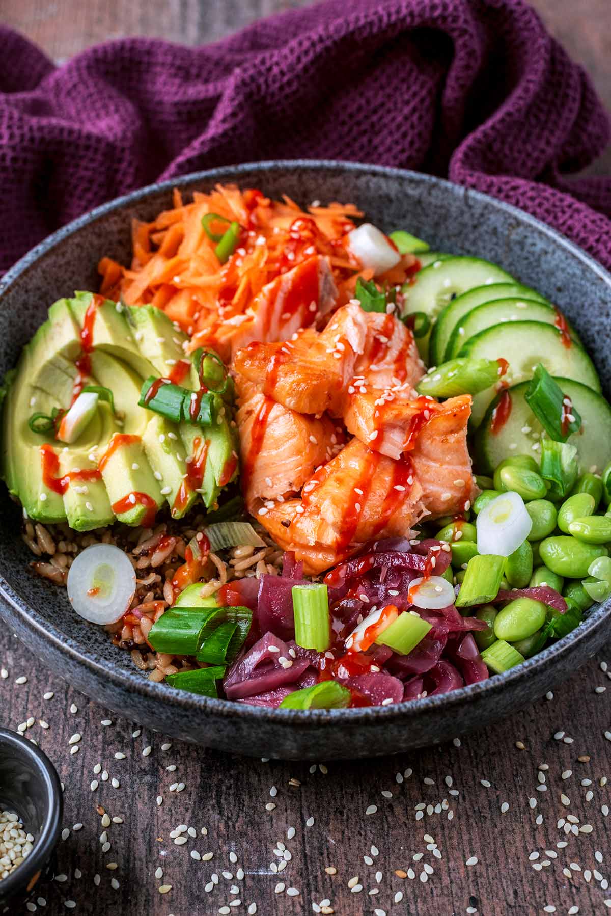 A bowl of salmon, rice and salad vegetables.