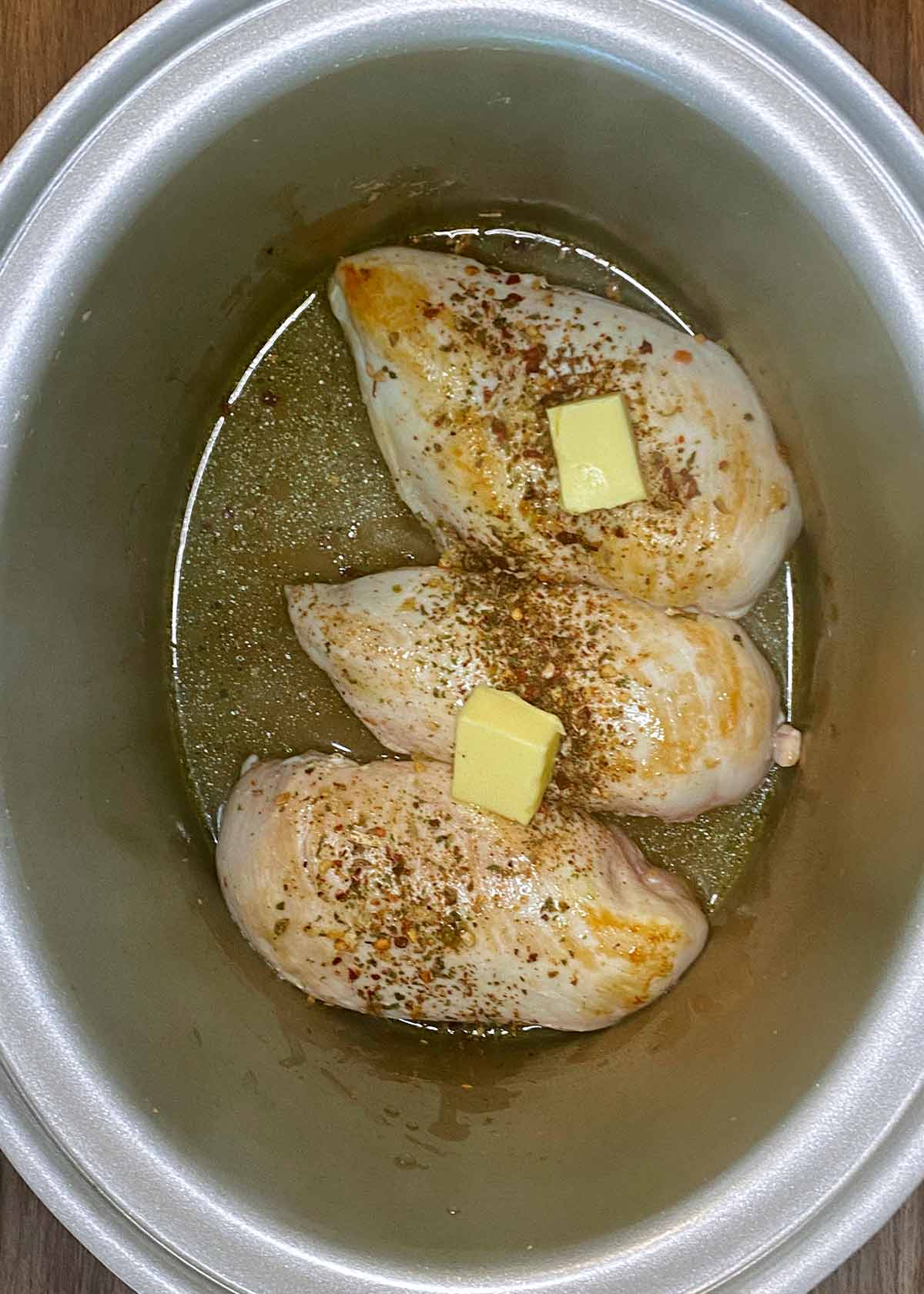 Stock, seasoning and butter added to the slow cooker.