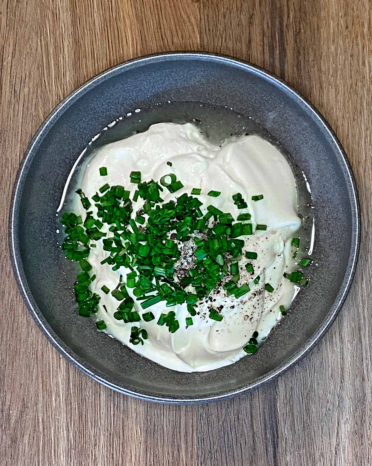 Cream, mayo, lemon juice and chopped chives in a bowl.