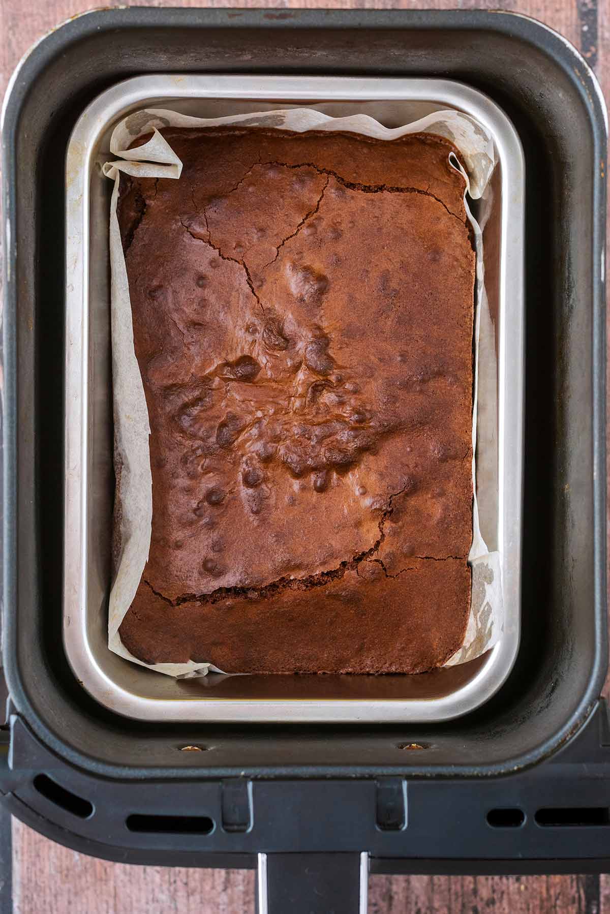 Cooked brownie in a tin in an air fryer basket.