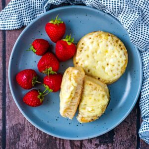 Two cheese covered air fryer crumpets, one is cut in half.