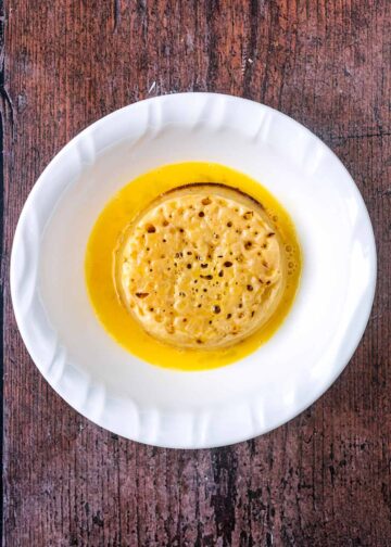 A crumpet in a bowl of whisked egg.