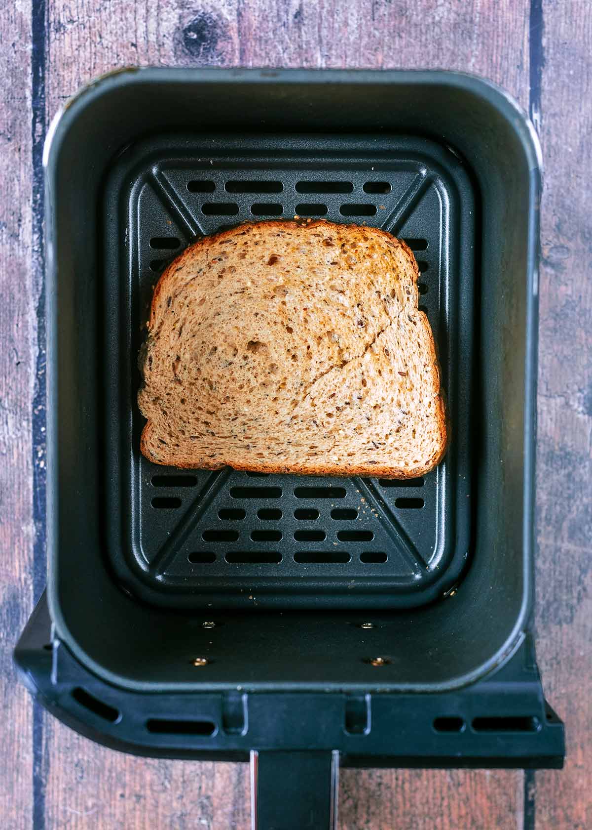 An air fryer basket with a slice of toast in it.