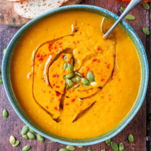 Canned pumpkin and carrot soup ion a bowl with a soup spoon.