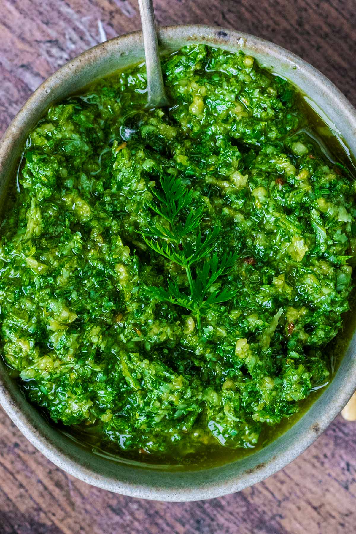 A vibrant green pesto with a sprig of carrot top on it.