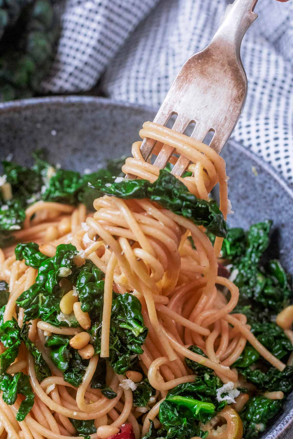 A fork lifting some cooked spaghetti and cavolo nero from a bowl.