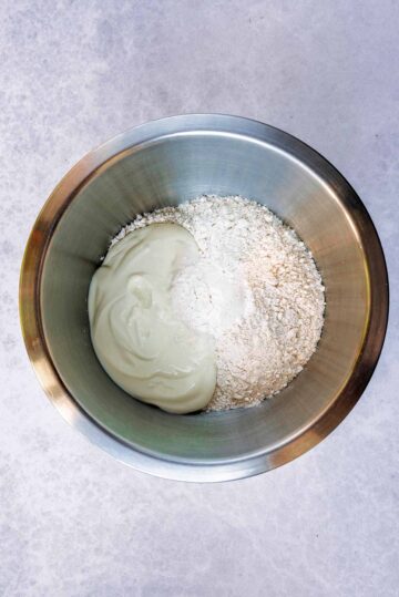 A large mixing bowl containing flour, baking powder and yogurt.