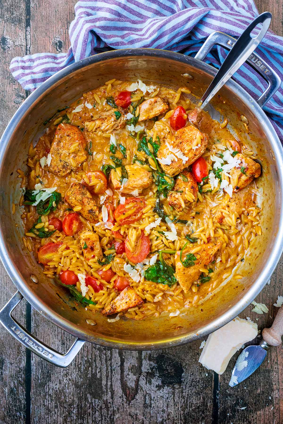 Chicken chunks, orzo and vegetables in a large silver pan.