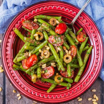A red bowl full of green bean salad.