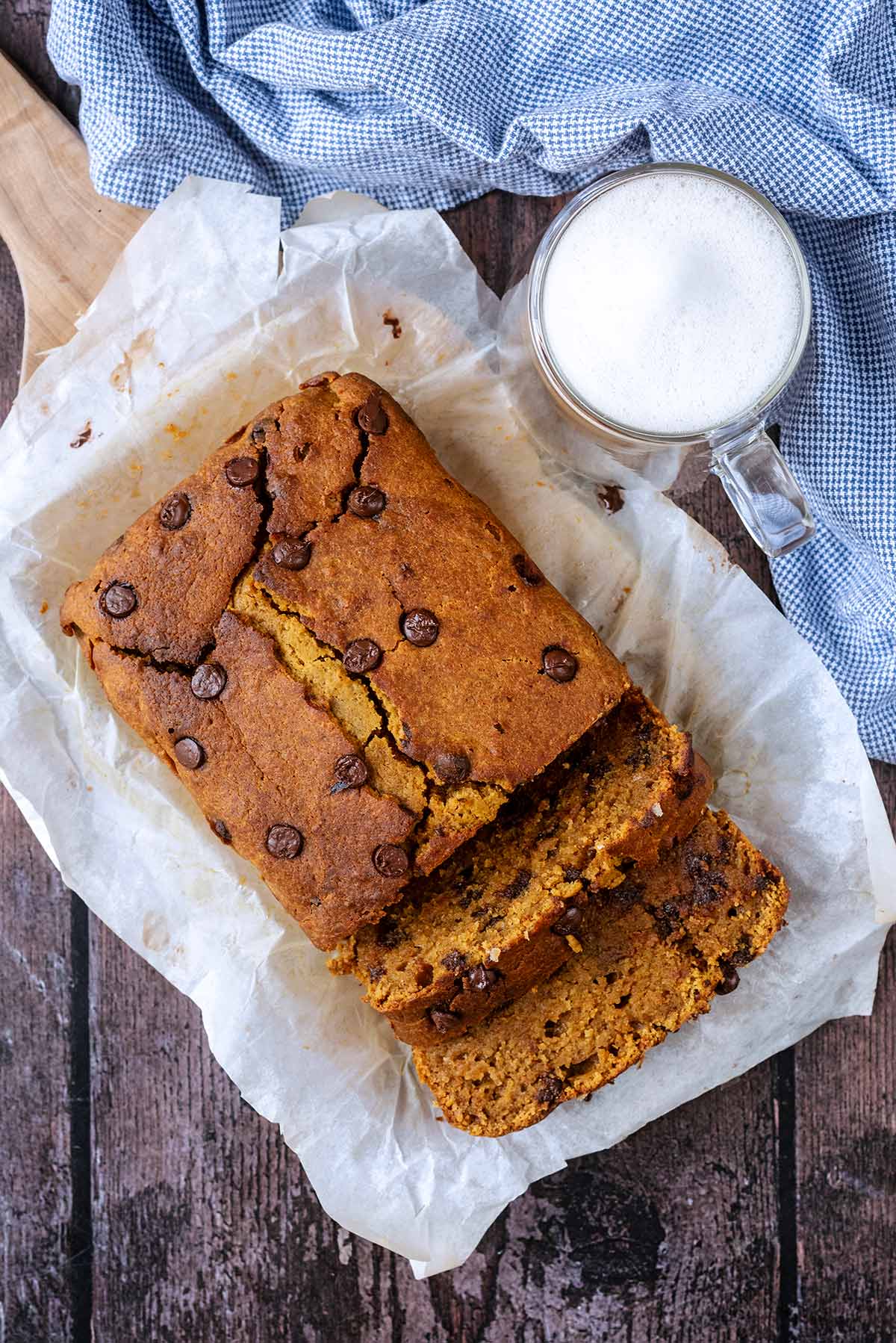 Chocolate chip loaf cake on a wooden surface with two slices cur off.