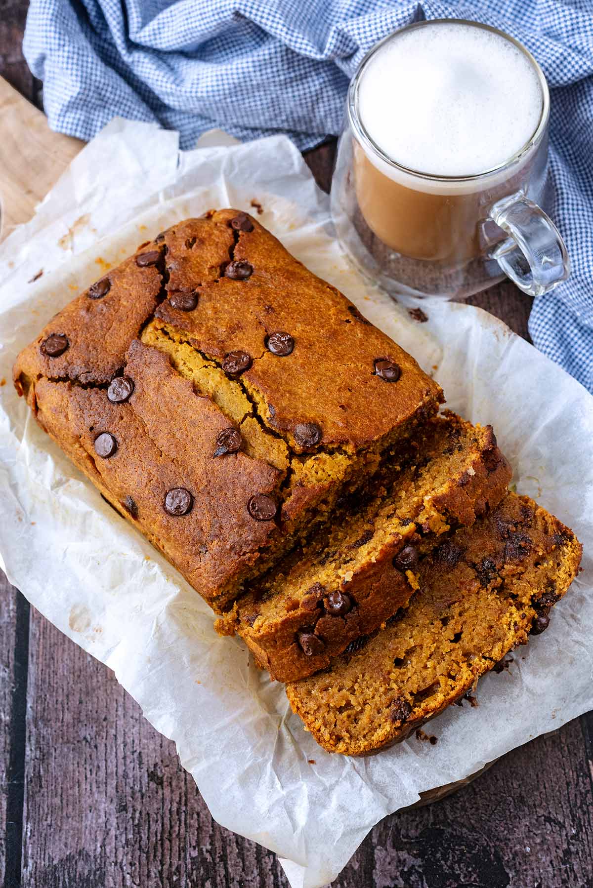 Pumpkin loaf cake next to a cup of coffee and a blue towel.