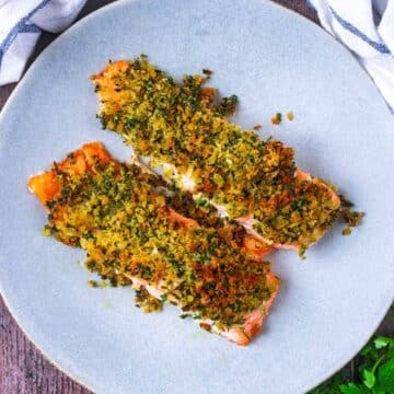 Two herb crusted salmon fillets on a grey plate.