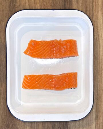 Two salmon fillets in a rectangular baking dish.