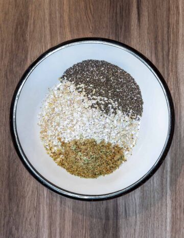 A bowl with oats, seeds and ground nuts in it.