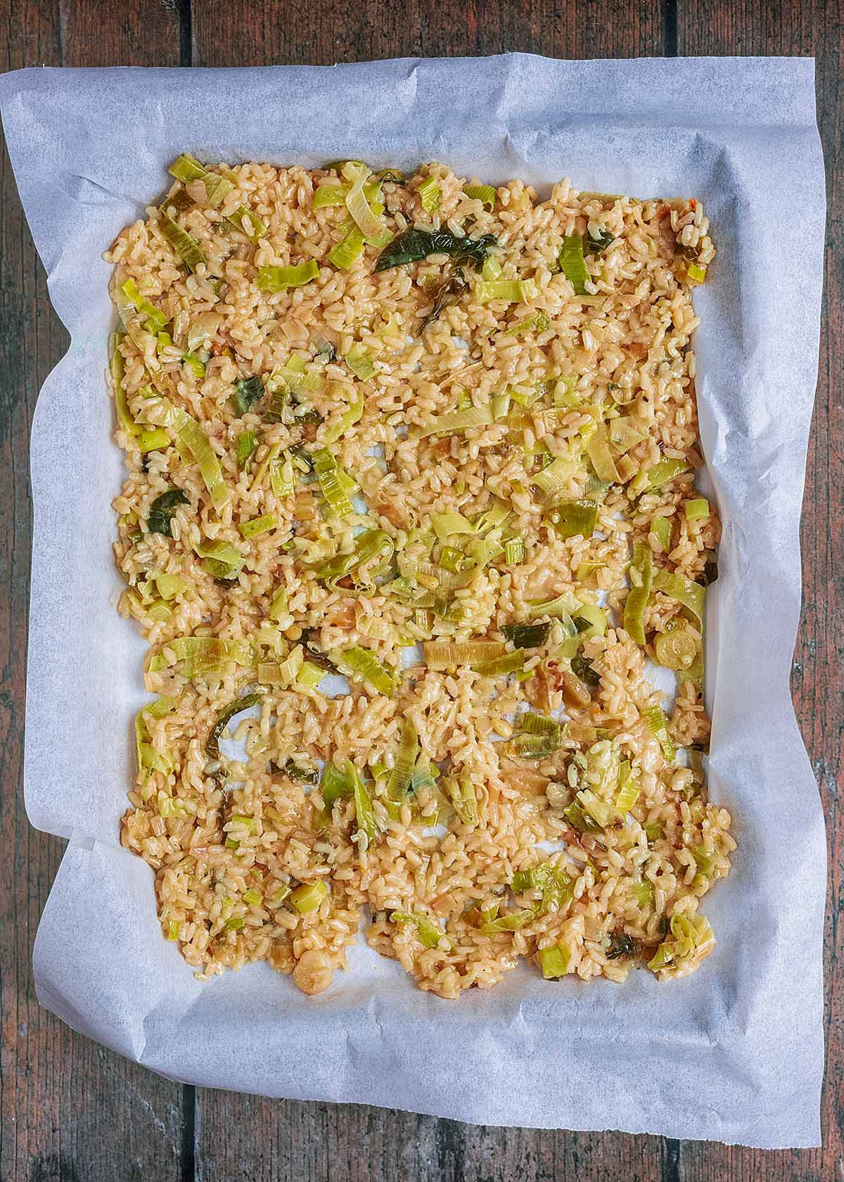 Risotto spread out over a lined baking sheet.