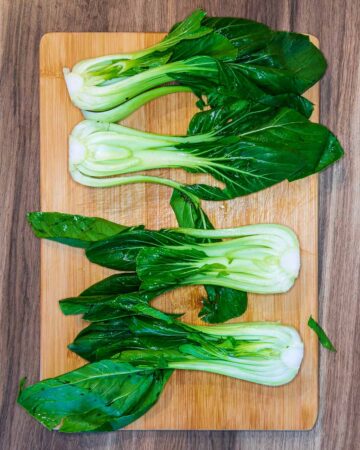 Four halves of pak choi on a chopping board.